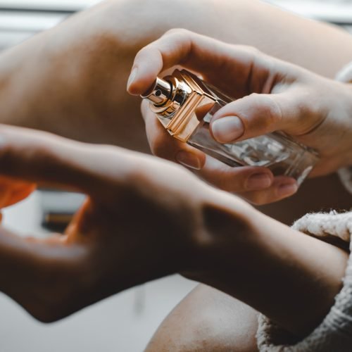 Young woman sprinkles perfume on her wrist. Perfume in a woman's hand